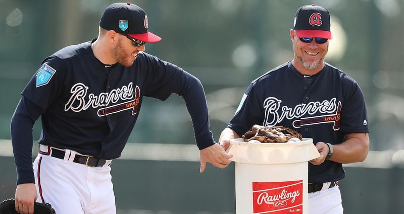 Even a Hall of Famer is not too big to lug around a few baseballs during spring training (here pictured with Braves first baseman Freddie Freeman). (Curtis Compton/ccompton@ajc.com)
