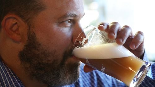 Rep. Kasey Carpenter samples his Space Force IPA, a teakwood-colored beer with citrus overtones. It was meant to mimic the Five Killer Citrus IPA that he produces at his Cherokee brewpub in Dalton. Curtis Compton/ccompton@ajc.com