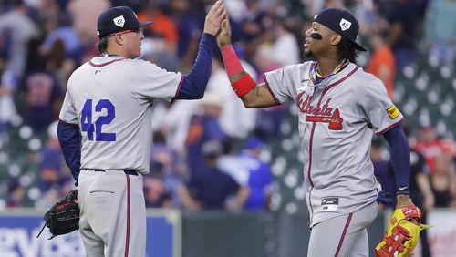 Braves closer Jesse Chavez, left, high-fives right fielder Ronald Acuna Jr., right, after their win over the Houston Astros in a baseball game Monday, April 15, 2024, in Houston. All players wore No. 42 in honor of Jackie Robinson Day. (AP Photo/Michael Wyke)