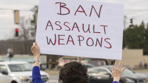 A woman holds a sign in during a protest against the National Rifle Association along Alabama Road NE in Woodstock, Tuesday, February 20, 2018. ALYSSA POINTER/ALYSSA.POINTER@AJC.COM