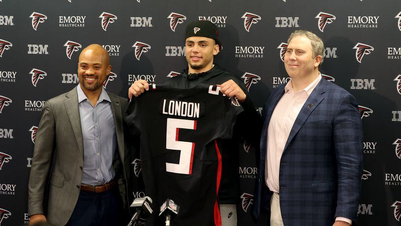 042922 Flowery Branch: Atlanta Falcons 2022 first round NFL draft pick Drake London, center, a wide receiver from USC, holds up his jersey with general manager Terry Fontenot, left, and head coach Arthur Smith, right, at the Falcons Practice Facility Friday, April 29, 2022, in Flowery Branch, Ga. (Jason Getz / Jason.Getz@ajc.com)