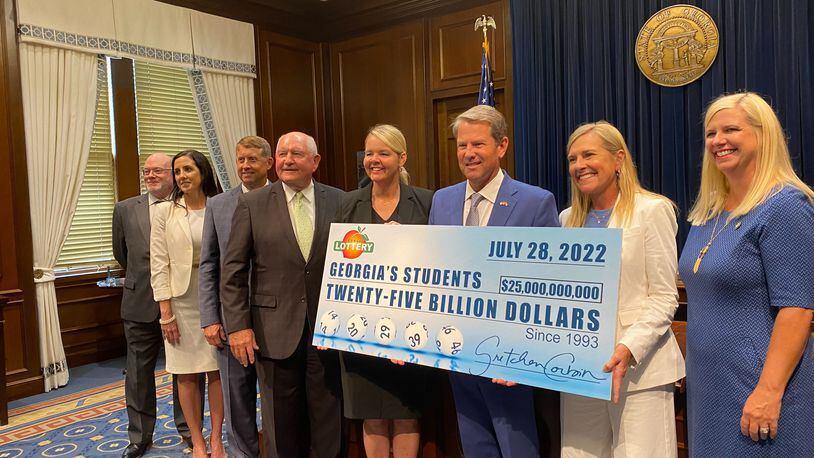 Gov. Brian Kemp holds a check representing how much money the Georgia Lottery has raised for education since 1993. Among those with Kemp at the news conference on Thursday, July 28, 2022, are Technical College System of Georgia Commissioner Greg Dozier (third from left), University System of Georgia Chancellor Sonny Perdue (fourth from left), Gretchen Corbin (fifth from left), CEO and president of the Georgia Lottery, and Kemp's wife, Marty (second from right). (Vanessa McCray / Vanessa.McCray@ajc.com)