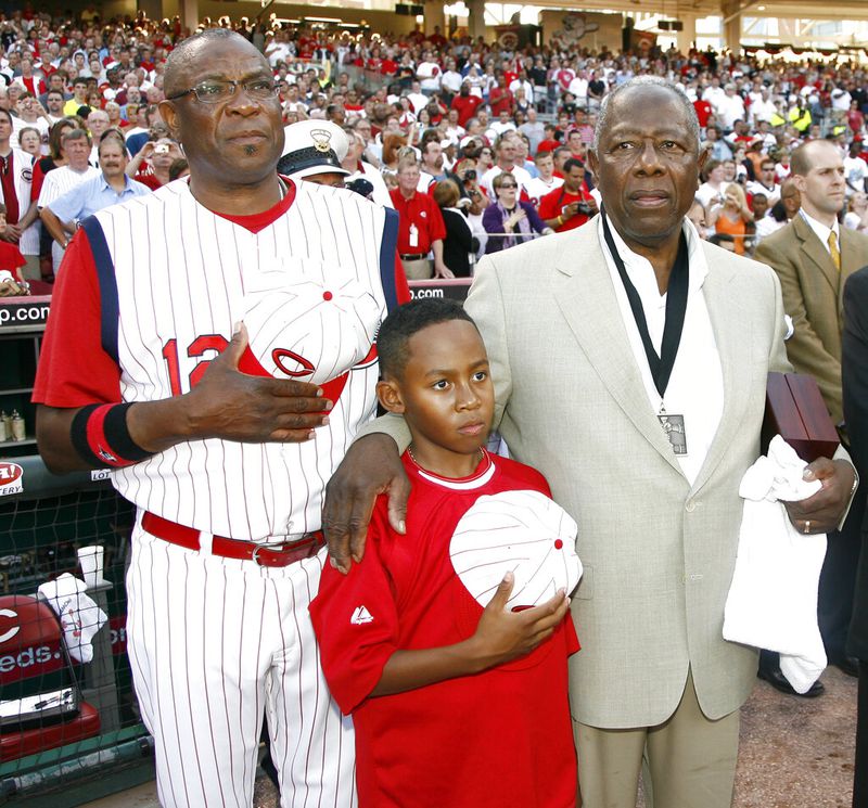 In this 2009 file photo, Reds manager Dusty Baker, left, stands with his son Darren Baker, center, and baseball great Hank Aaron as the national anthem is played at the Civil Rights Game ceremony before a game.   (AP Photo/David Kohl, File)