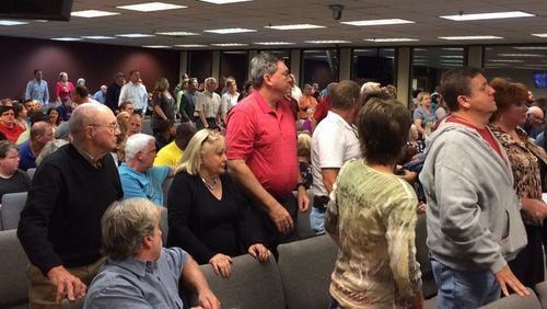 Residents against a complex for disabled adults being built near a Hall County neighborhood stand in a county commission meeting to show their opposition. Photo by Bill Torpy.