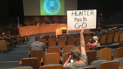 A protester holds a sign calling for the resignation of embattled Gwinnett Commissioner Tommy Hunter during a recent Gwinnett County Board of Commissioners meeting. TYLER ESTEP / TYLER.ESTEP@AJC.COM