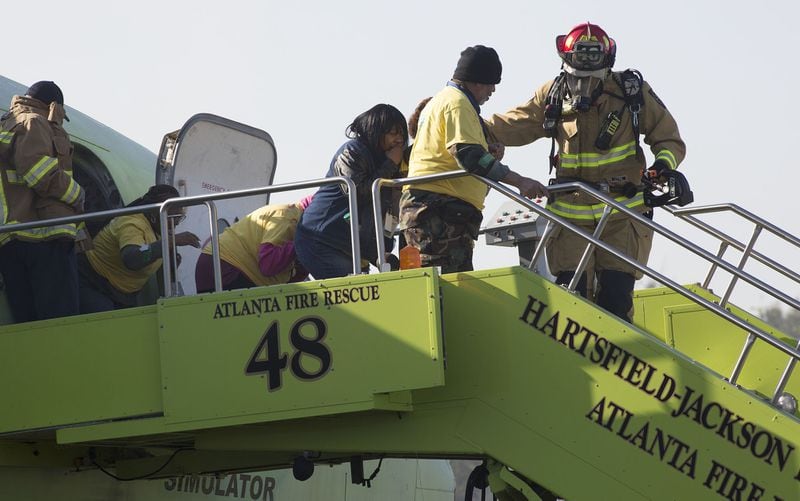 Firefighters helped "victims" off a plane as Hartsfield-Jackson International Airport held a full-scale disaster drill with Atlanta Firefighters, law enforcement, rescue personnel and nearly 150 volunteers who participated in a triennial exercise known as âBig Birdâ on Thursday, April 12, 2018. Airport personnel mobilized to a mock aircraft crash, extinguished the fire then triaged & treated the victims at a training site. The Federal Aviation Administration requires airports to conduct annual emergency preparedness drills and at least one full-scale drill every three years. (Photo by Phil Skinner)NOTE: getting Ids was impossible because the media was too far away.