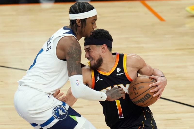 Phoenix Suns guard Devin Booker (1) tries to get past Minnesota Timberwolves forward Jaden McDaniels, left, during the second half of Game 4 of an NBA basketball first-round playoff series Sunday, April 28, 2024, in Phoenix. The Timberwolves won 122-116, taking the series 4-0. (AP Photo/Ross D. Franklin)