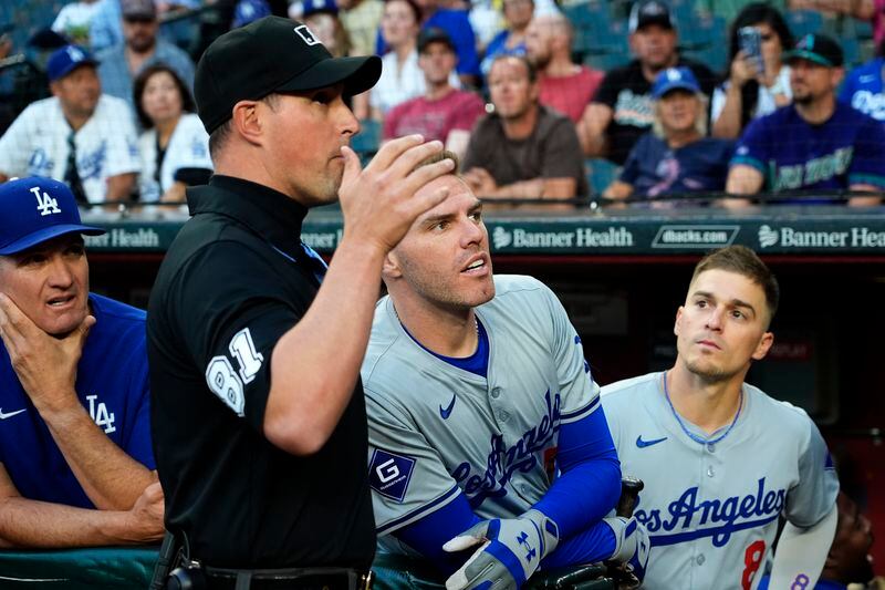 Los Angeles Dodgers Freddie Freeman and umpire Quinn Wolcott watch a swarm of bees gather on the net behind home plate delaying the start of a baseball game between the Los Angeles Dodgers and the Arizona Diamondbacks, Tuesday, April 30, 2024, in Phoenix. (AP Photo/Matt York)