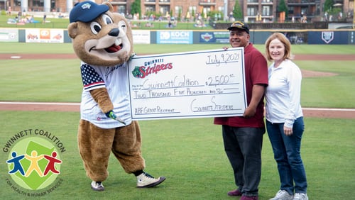 Chopper, the Gwinnett Stripers' mascot, delivers a $2,500 check to representatives of the Gwinnett Coalition during a July 9 home game. (Courtesy of Gwinnett Stripers)