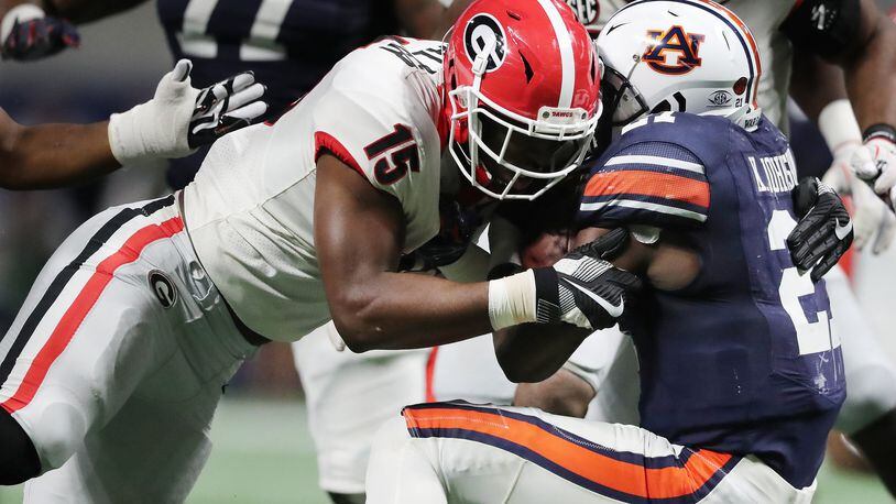 Georgia linebacker D’Andre Walker levels Auburn running back Kerryon Johnson during the SEC Football Championship at Mercedes-Benz Stadium Dec. 2 in Atlanta. UGA stopped tracking concussions by sport once the school had completed a grant application to study the injury. CURTIS COMPTON / CCOMPTON@AJC.COM