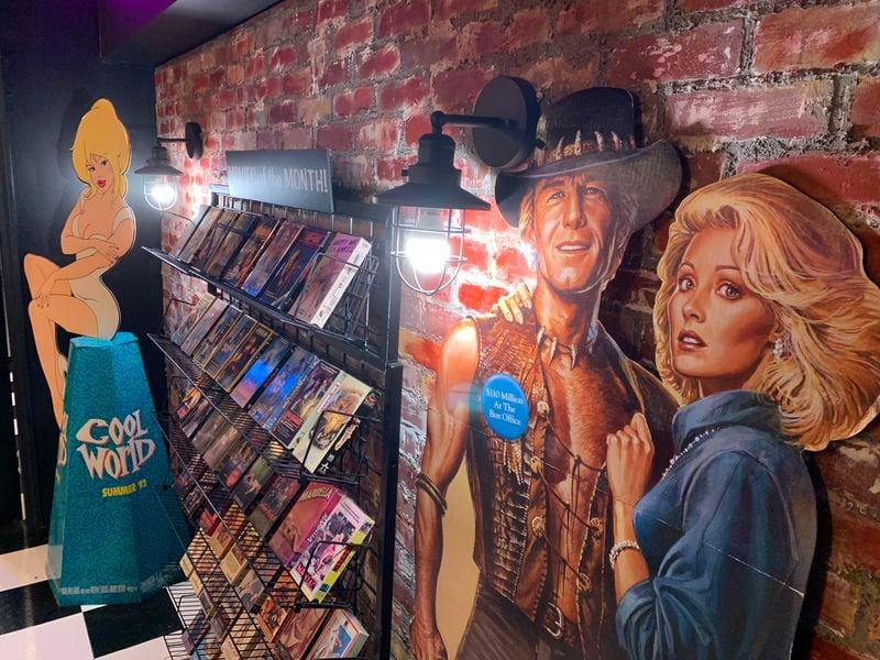 Anthony SantAnselmo's replica video rental store in his basement features oversized cardboard cutouts of films "Cool World" and "Crocodile Dundee II." RODNEY HO/rho@ajc.com