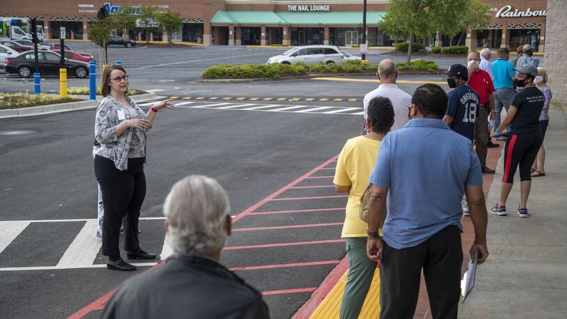 Gwinnett County elections supervisor Kristi Royston (left) gives instructions to individuals waiting in line for early in-person voting at the Gwinnett County Voter Registration and Elections Office in Lawrenceville, Monday, May 18, 2020. (ALYSSA POINTER / ALYSSA.POINTER@AJC.COM) AJC FILE PHOTO