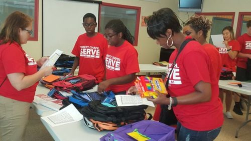 Volunteers fill back packs with back-to-school supplies for needy families as part of worldwide Serve Day 2017.