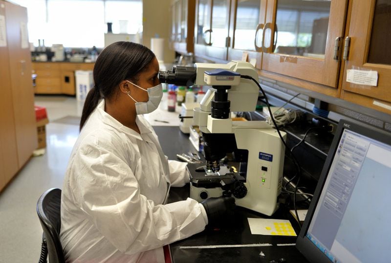 Lanisha Gittens, a forensic scientist for the Georgia Bureau of Investigation, searches for DNA evidence at the agency’s Decatur-area crime lab. Although rape victims, regardless of whether they report the crimes to police, are entitled by law to a free exam for evidence collection, GBI only analyzes samples for open cases. BRANT SANDERLIN/BSANDERLIN@AJC.COM