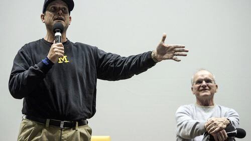 Michigan head coach Jim Harbaugh speaks during the 2016 Michigan Coaches' Clinic, Friday, March 11, 2016, in Ann Arbor, Mich. Listening at right is his father Jack Harbaugh. (Junfu Han/The Ann Arbor News via AP) LOCAL TELEVISION OUT; LOCAL INTERNET OUT; MANDATORY CREDIT