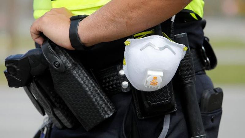 A North Charleston police officer carries a protective mask around his gun belt while working traffic at Roper St. Francis' North Charleston office Monday, March 16, 2020, in North Charleston, S.C.  (AP Photo/Mic Smith)