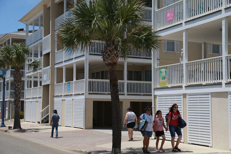 Visitors to Tybee Island walk along Strand Avenue past multiple short-term vacation rentals.