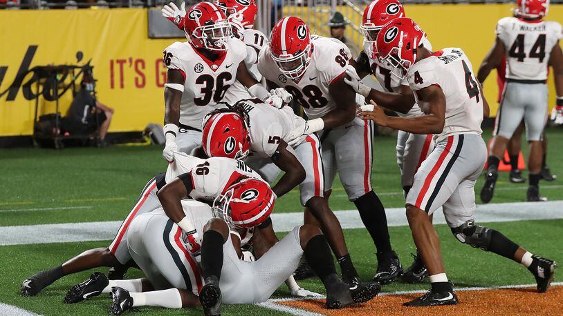 Teammates pile on Georgia defensive back Christopher Smith in the end zone after he intercepted a pass intended for Clemson wide receiver Justyn Ross and returned it for a touchdown during the second quarter Saturday, Sept 4, 2021, in Charlotte, N.C. The Bulldogs took a 7-0 lead. (Curtis Compton / Curtis.Compton@ajc.com)