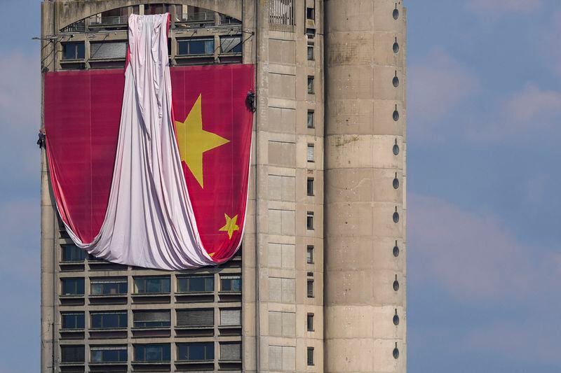 Workers hang on ropes to install a giant Chinese national flag on a skyscraper that is a symbolic gateway leading into the city from the airport, in Belgrade, Serbia, Saturday, May 4, 2024. Chinese leader Xi Jinping's visit to European ally Serbia on Tuesday falls on a symbolic date: the 25th anniversary of the bombing of the Chinese Embassy in Belgrade during NATO's air war over Kosovo. (AP Photo/Darko Vojinovic)