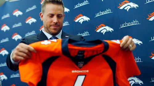 Case Keenum looks over his new jersey during a news conference to introduce him as the new starting quarterback of the Denver Broncos at the team's headquarters Friday, March 16, 2018, in Englewood, Colo.  (AP Photo/David Zalubowski)