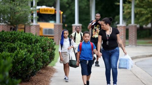 First-grade student Josiel Cartagena walks with his mother Natasha Cruz on Aug. 3 for the first day of classes at Anderson Elementary School in Clayton County. (Jason Getz / Jason.Getz@ajc.com)