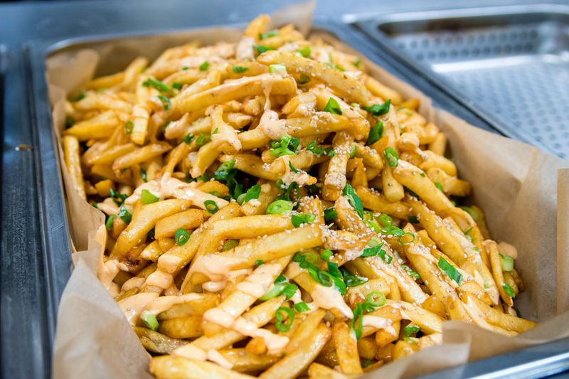 French fries fresh from the fryer, sprinkled with chives, sesame seeds and spicy mayo. CONTRIBUTED BY HENRI HOLLIS