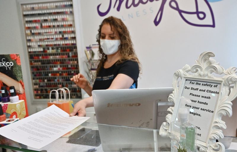 Paris Campeau, owner, printed out a waiver form before she serves a customer at Indigo Wellness Spa in Kirkwood on Wednesday, May 27, 2020. Paris Campeau didn’t open her wellness boutique when the governor said she could a month ago, but now, with bills piling up and some clients ready to come by, she’s giving it a shot. (Hyosub Shin / Hyosub.Shin@ajc.com)