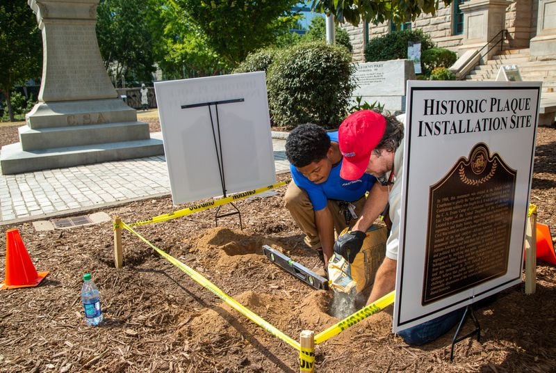Warren Crawley II (left) & JP Coirin, from Fast Signs of Tucker, pour cement for the foundation of a contextual marker on site of the Confederate monument in downtown Decatur, which is owned by DeKalb County. (Photo by Phil Skinner)
