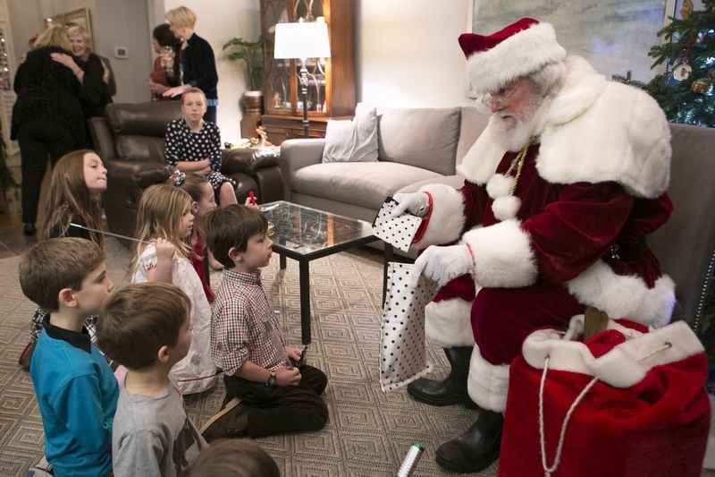 Judge T. Jackson Bedford (right), aka Santa Claus, performs magic tricks for children at a house Christmas party in Smyrna. CASEY SYKES / FOR THE ATLANTA JOURNAL-CONSTITUTION