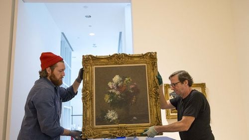 High Museum of Art chief preparer Brian Kelly (right) and Bonsai Fine Art museum preparer Seth Dalton (left) handle a Henri Fantin-Latour painting inside the Doris and Shouky Shaheen gallery at the High Museum of Art. (Alyssa Pointer/Atlanta Journal Constitution)