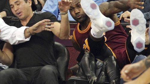 Cleveland Cavaliers' LeBron James falls into Ellie Day, wife of PGA Tour golf player Jason Day, at left, during the second half of an NBA basketball game against the Oklahoma City Thunder, Thursday, Dec. 17, 2015, in Cleveland. (John Kuntz/The Plain Dealer via AP) MANDATORY CREDIT; NO SALES