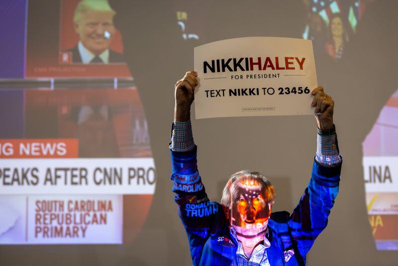 David Wertz of Charleston holds a sign in front of a projector at Republican presidential candidate Nikki Haley’s primary day watch party at The Charleston Place in Charleston, South Carolina on Saturday, February 24, 2024, after CNN projected former president and Republican presidential candidate Donald Trump won Haley’s home state. (Arvin Temkar / arvin.temkar@ajc.com)