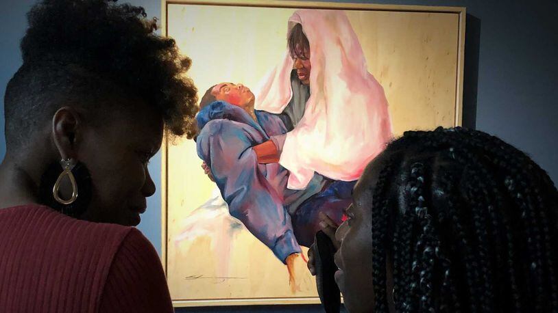 Shanequa Gay (left) discusses her painting "La Pieta," with Isuan Oyakhire, an Oglethorpe senior biopsychology major, after its unveiling at the university’s art museum.