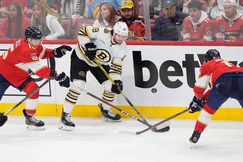 Boston Bruins center Pavel Zacha (18) passes the puck past Florida Panthers center Evan Rodrigues (17) and center Anton Lundell (15) during the second period of Game 1 of the second-round series of the Stanley Cup Playoffs, Monday, May 6, 2024, in Sunrise, Fla. (AP Photo/Wilfredo Lee)