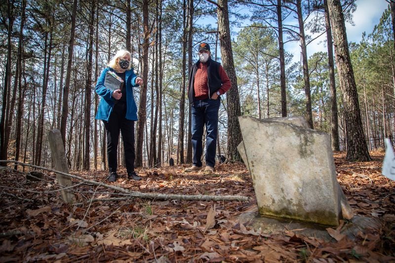 Johns Creek's Historical Society co-founder Joan Compton and board member Kirk Canaday look over a headstone at Macedonia African Methodist Church Cemetery. STEVE SCHAEFER for the AJC