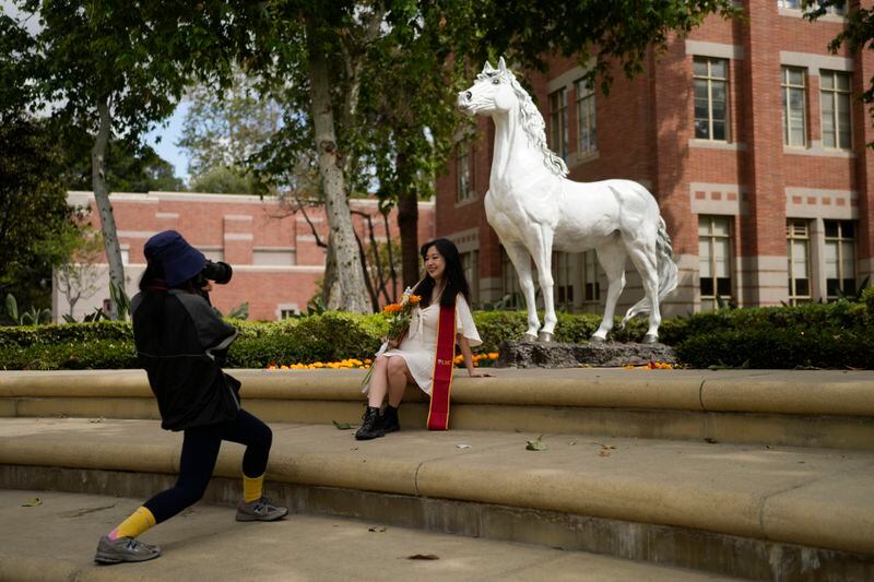 A recent graduate has their photograph taken in front of the school's mascot on the USC campus Thursday, April 25, 2024, in Los Angeles. The University of Southern California has canceled its main graduation ceremony and dozens of students were arrested on other campuses as protests against the Israel-Hamas war continued to spread. (AP Photo/Jae C. Hong)