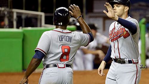 Atlanta Braves' Justin Upton (8) greets Freddie Freeman, right, at the plate after they scored on a double by Evan Gattis in the fourth inning during a baseball game against the Miami Marlins, Monday, Sept. 9, 2013 in Miami. (AP Photo/Lynne Sladky)