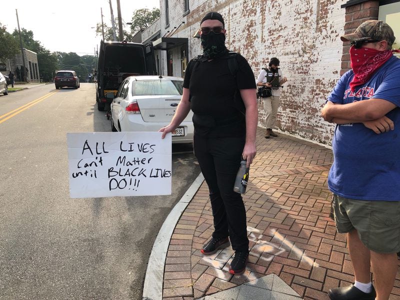 Atlanta activist Zach Benton holds a sign in downtown Stone Mountain Saturday, May 15, 2020.