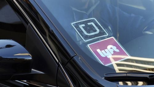 A ride-share car displays Lyft and Uber stickers on its front windshield in downtown Los Angeles. A North Georgia Republican has introduced legislation that would allow Lyft and Uber drivers to keep firearms in their cars. (AP Photo/Richard Vogel, File)
