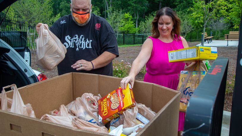 Jason Creed (left) helps Crystal Genter, of the architectural firm Goode Van Slyke, unload donations from her car at the Atlanta Community Food Bank in East Point. The firm is celebrating its 25th anniversary by doing 25 good deeds. PHIL SKINNER FOR THE ATLANTA JOURNAL-CONSTITUTION.