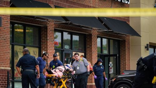 Medical personnel take a gunshot victim to a waiting ambulance outside the Luxury Nail Salon on Cleveland Avenue in East Point.