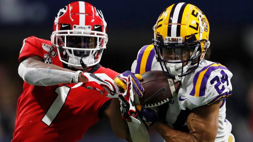 FILE - In this Dec. 7, 2019, file photo, LSU cornerback Derek Stingley Jr. (24) intercepts the ball from Georgia wide receiver George Pickens (1) during the second half of the Southeastern Conference championship NCAA college football game in Atlanta. Southeastern Conference schools will be able to bring football and basketball players back to campus for voluntary activities starting June 8 at the discretion of each university. The SEC’s announcement Friday, May 22, 2020, is the latest sign of encouragement that a college football season in at least some form can go on this fall.(AP Photo/John Bazemore, File)