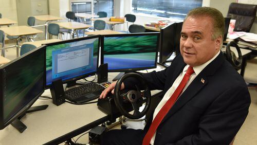 Alan Brown with a driving simulator at Cartersville High School. Following the death of his teenage son, Brown pushed for a law that mandated drivers’ education, Joshua’s Law, to be paid for with fees on speeding tickets. BRANT SANDERLIN/BSANDERLIN@AJC.COM