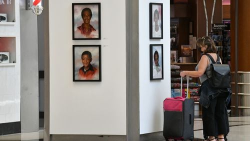 June 30, 2021 Atlanta - Airport travelers appreciate the exhibition of the Atlanta ChildrenÕs Memorial Portraits at Hartsfield-Jackson Atlanta International Airport on Wednesday, June 30, 2021. Hartsfield-Jackson Honors Atlanta Child Murder Victims with Portrait Art Exhibit ATLÕs award-winning art program is hosting the Atlanta ChildrenÕs Memorial Portraits exhibition from June 25 Ð Sept. 8, 2021. Selected from a competition of over 100 regional visual art professionals, artist Dwayne Mitchell was commissioned to create 30 portraits memorializing each victim of the Atlanta Child Murders. (Hyosub Shin / Hyosub.Shin@ajc.com)