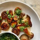 Dark golden brown seared king trumpet and white button mushrooms are topped with zesty lemon gremolata, with an additional bowl of the herby sauce on the side. (Virginia Willis for The Atlanta Journal-Constitution)