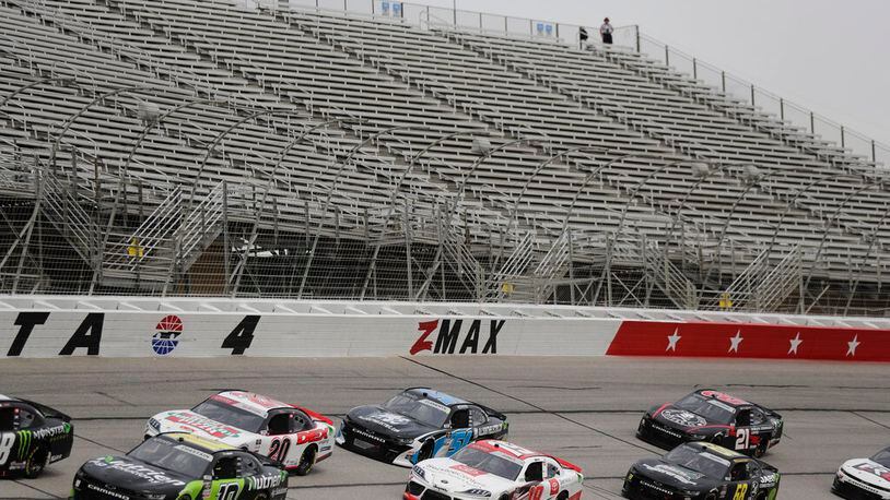 Cars drive by empty stands during a NASCAR Xfinity Series auto race at Atlanta Motor Speedway on Saturday, June 6, 2020, in Hampton, Ga. (AP Photo/Brynn Anderson)