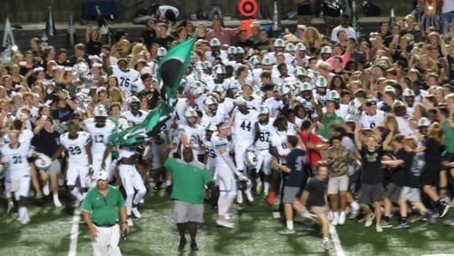 The Roswell Hornets charge the field with their fans follwoing their 22-20 win over the Milton Eagles on Friday, Sept. 12, 2018 at Eagles’ Nest in Milton. (Adam Krohn/AJC)