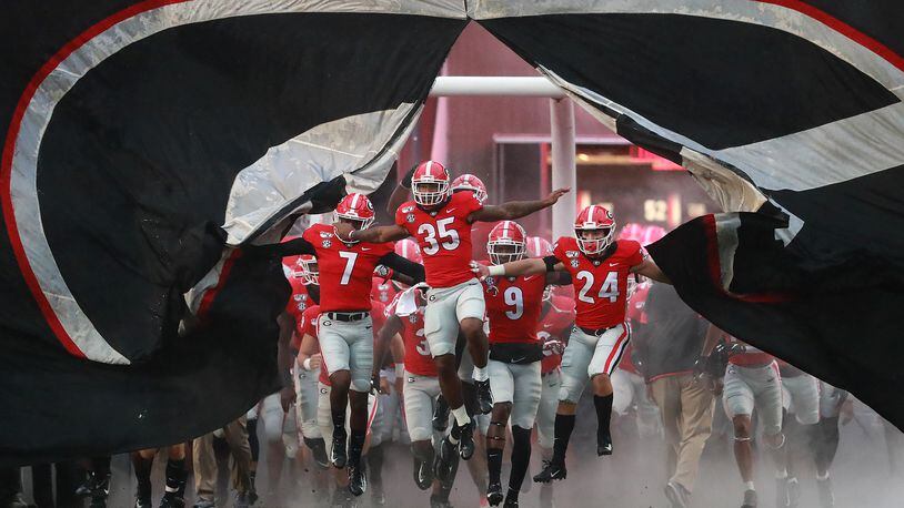 Georgia players break through the giant banner while taking the field.    Curtis Compton/ccompton@ajc.com
