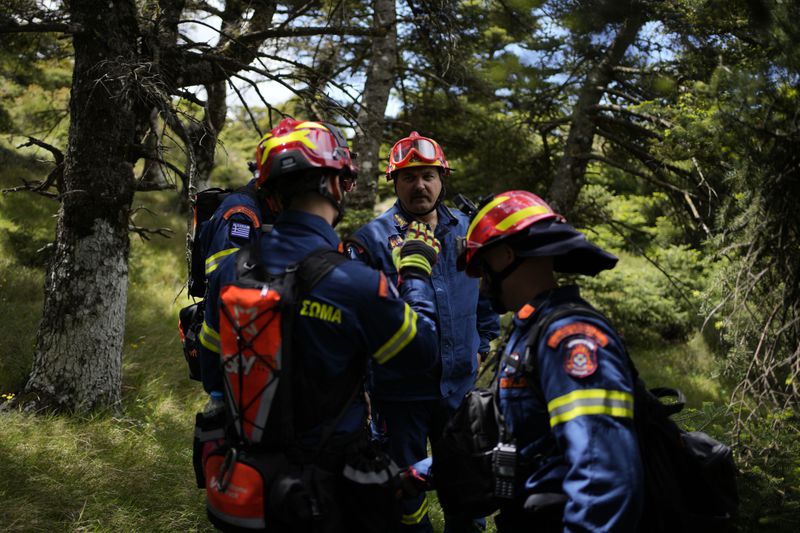Fire Lt Col Ioannis Kosovo's, head of the 1st Wildfire Special Operation Unit, center, speaks with the members of his team during a drill near Villia village some 60 kilometers (37 miles) northwest of Athens, Greece, Friday, April 19, 2024. Greece's fire season officially starts on May 1 but dozens of fires have already been put out over the past month after temperatures began hitting 30 degrees Celsius (86 degrees Fahrenheit) in late March. This year, Greece is doubling the number of firefighters in specialized units to some 1,300, adopting tactics from the United States to try and outflank fires with airborne units scrambled to build breaks in the predicted path of the flames. (AP Photo/Thanassis Stavrakis)