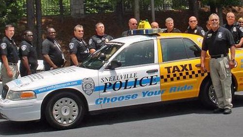 Snellville Councilmember Bobby Howard with Snellville Police Officers and the city’s Cop Cab, designed to increase awareness of the consequences of driving under the influence of drugs and alcohol. Courtesy City of Snellville